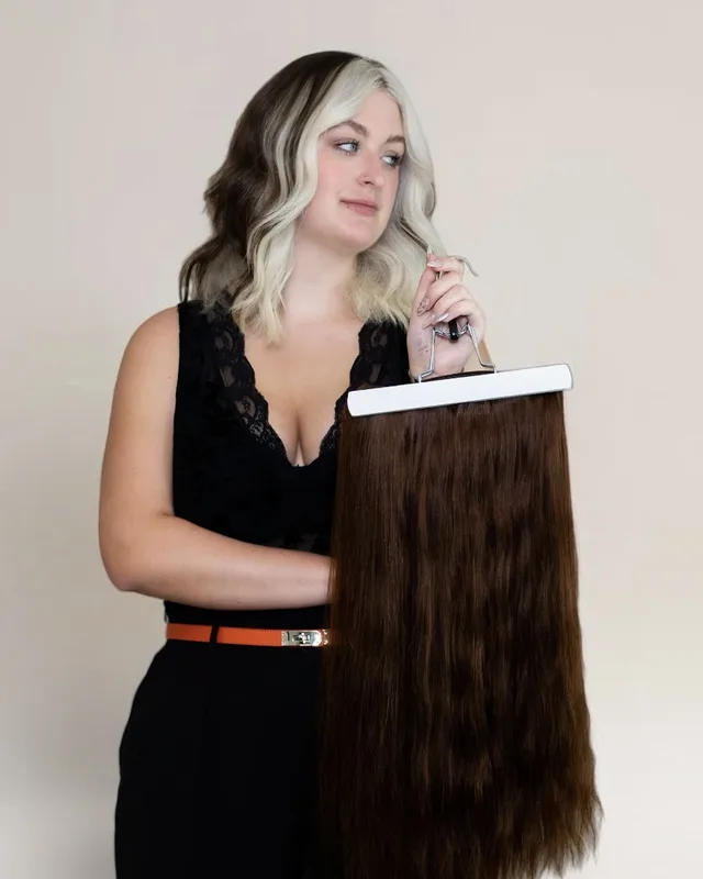 Portrait of Baylee holding a weft of brunette hair extensions, Emerging Stylist for hair color and extensions at Infinite Hair Studio in Baton Rouge, LA