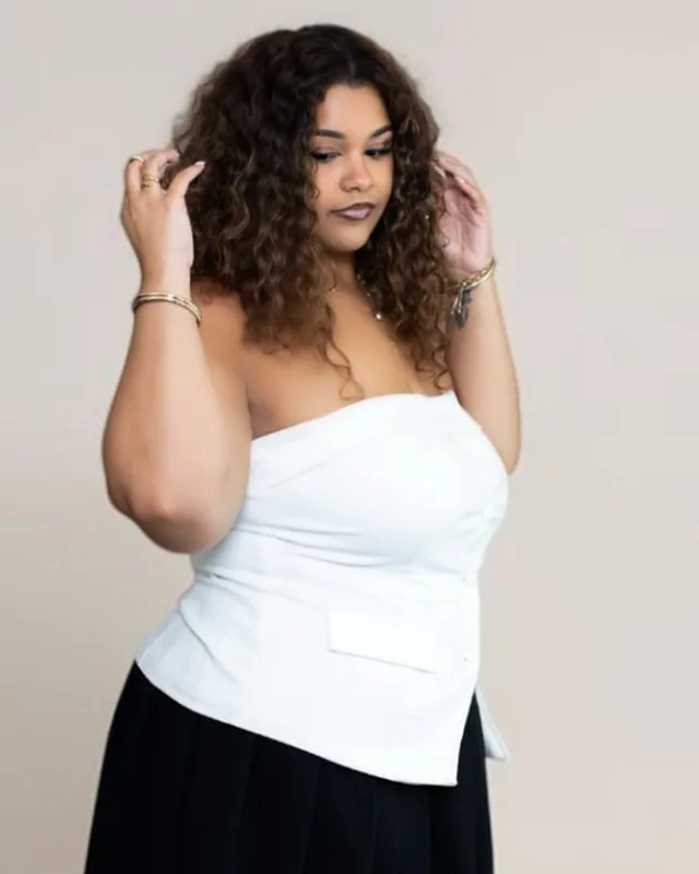 Portrait of Bre with defined natural curls in a white top, Specialty Stylist for curly hair and vivid color at Infinite Hair Studio in Baton Rouge, LA
